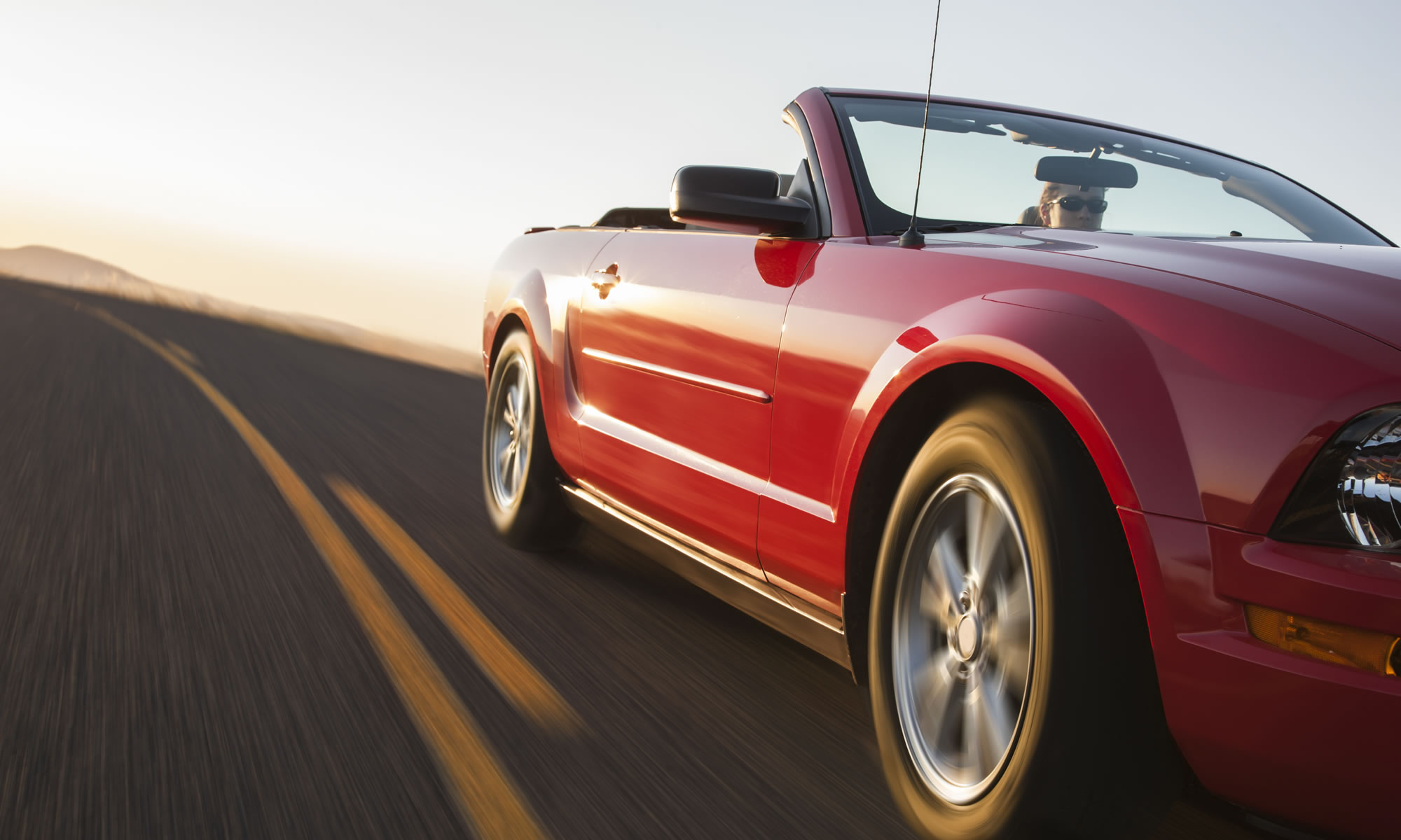 Red convertible car driving on an open road